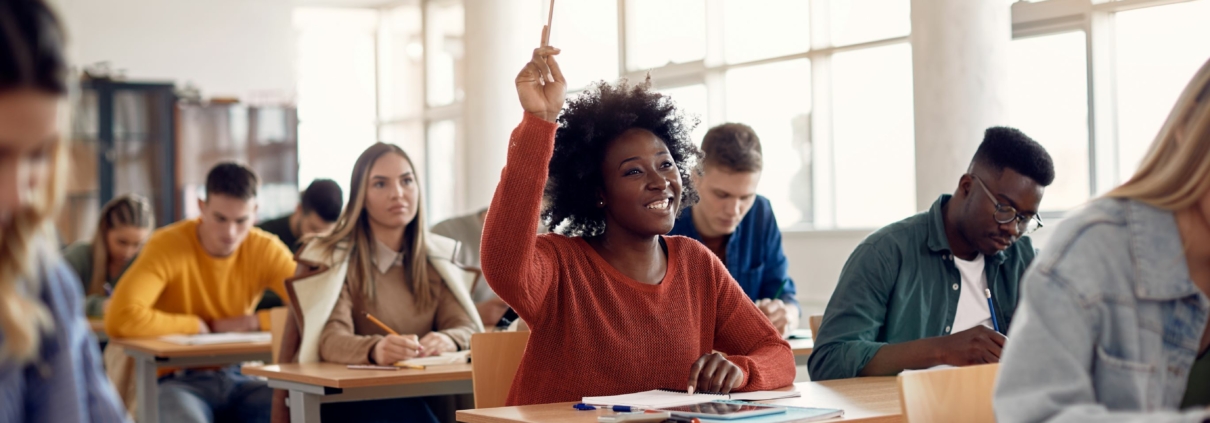 university student raising her hand with a pencil to ask or answer a question in a classroom setting