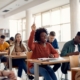 university student raising her hand with a pencil to ask or answer a question in a classroom setting